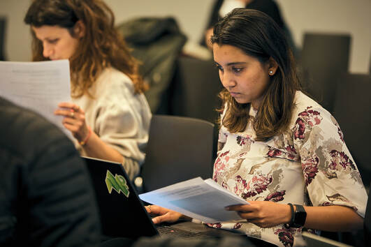 Woman looking at laptop with papers on left hand