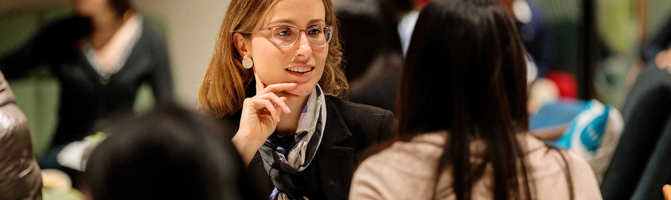 Two women having a conversation on a crowded room