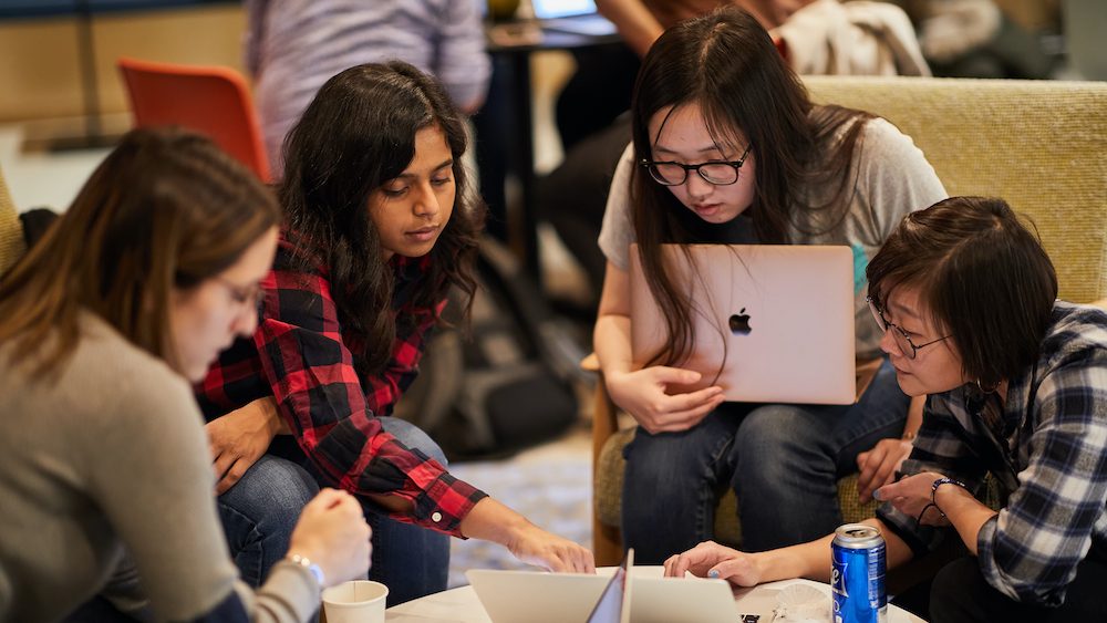 group of women huddled together working on datathon